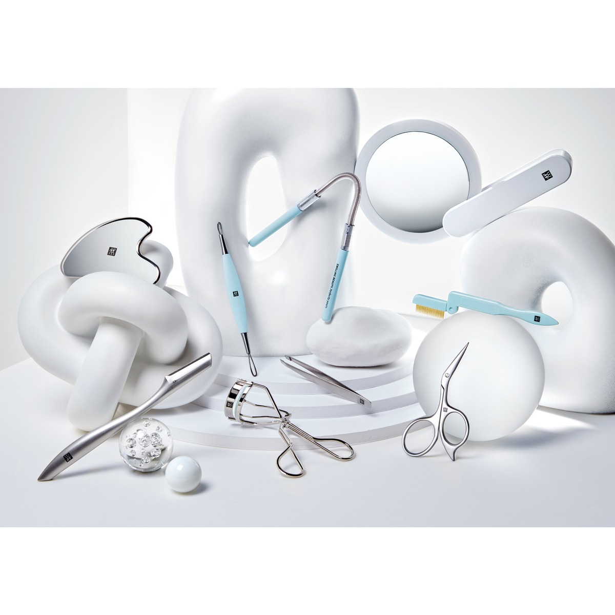 Darstellung des ZWILLING Premium LED-Kosmetikspiegels zusammen mit weiteren ZWILLING Produkten inmitten von artifiziellen Marmorobjekten.
