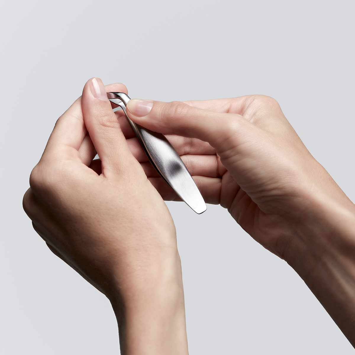 Anwendung eines ZWILLING Premium Nagelhautschiebers aus rostfreiem Edelstahl an der Nagelhaut des linken Daumens.
