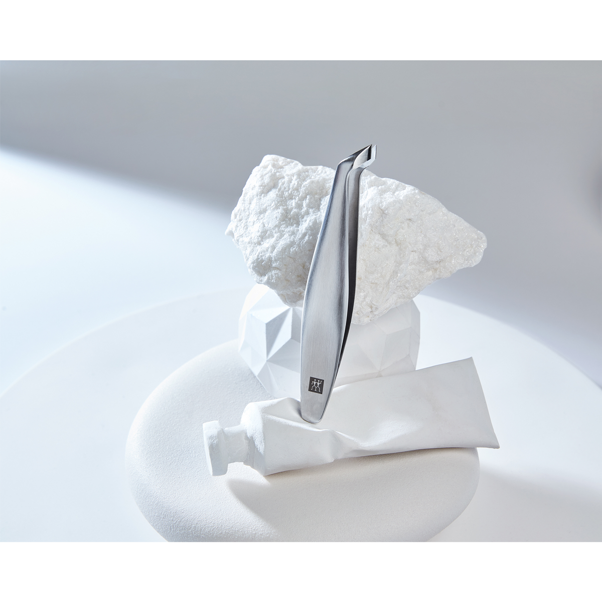 Darstellung des ZWILLING Premium Nagelhautschiebers aus rostfreiem Edelstahl positioniert auf diversen, artifiziellen Objekten.